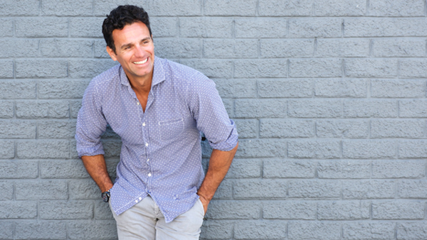 Man leaning on gray brick wall